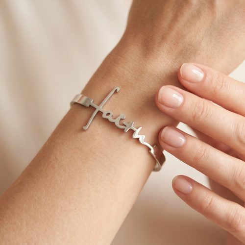 Zilveren armband met het woord faith gedragen om de pols