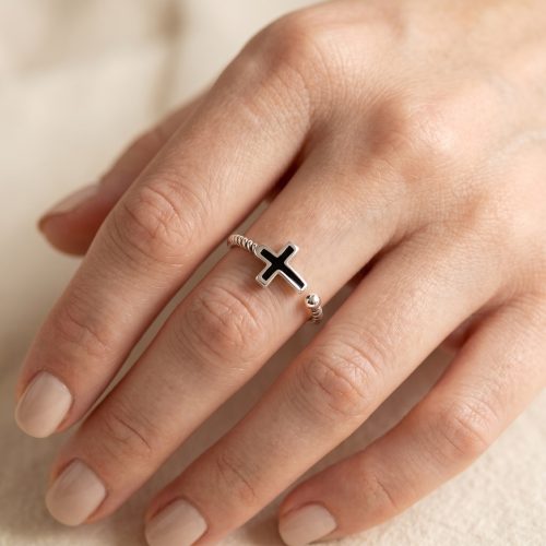 Zilveren ring met zwart kruisje gedragen aan de hand