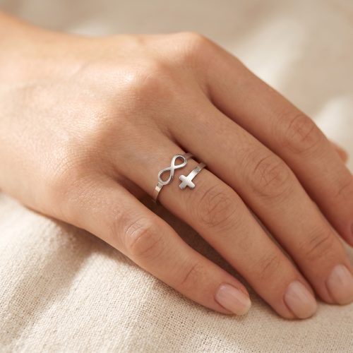 Zilveren ring met kruisje en infinity-symbool gedragen aan de hand