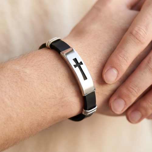 Zwarte siliconen herenarmband met kruis gedragen om een mannenpols