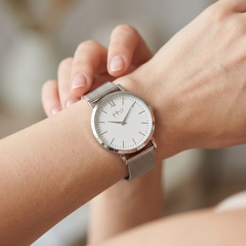 Minimalistisch horloge met mesh-bandje gedragen om de pols